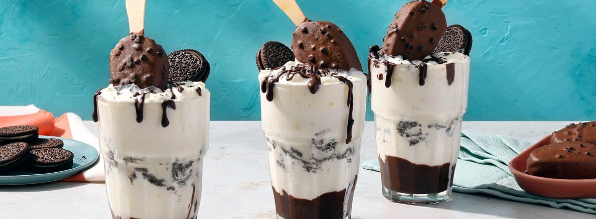Three Cookies and Cream Ice Cream Floats topped with Cookies & Cream ice cream bars, an Oreo and chocolate syrup