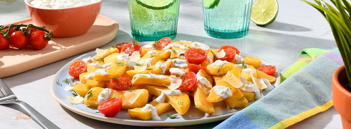 French fries on a plate topped with Wedge Salad Dip, fresh tomatoes, and chopped dill.