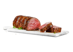 A cooked beef tenderloin road has two pieces cut off, resting on a cutting board