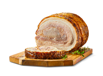 A pork porchetta roast with a slice cut, sitting on a wooden cutting board with some herbs